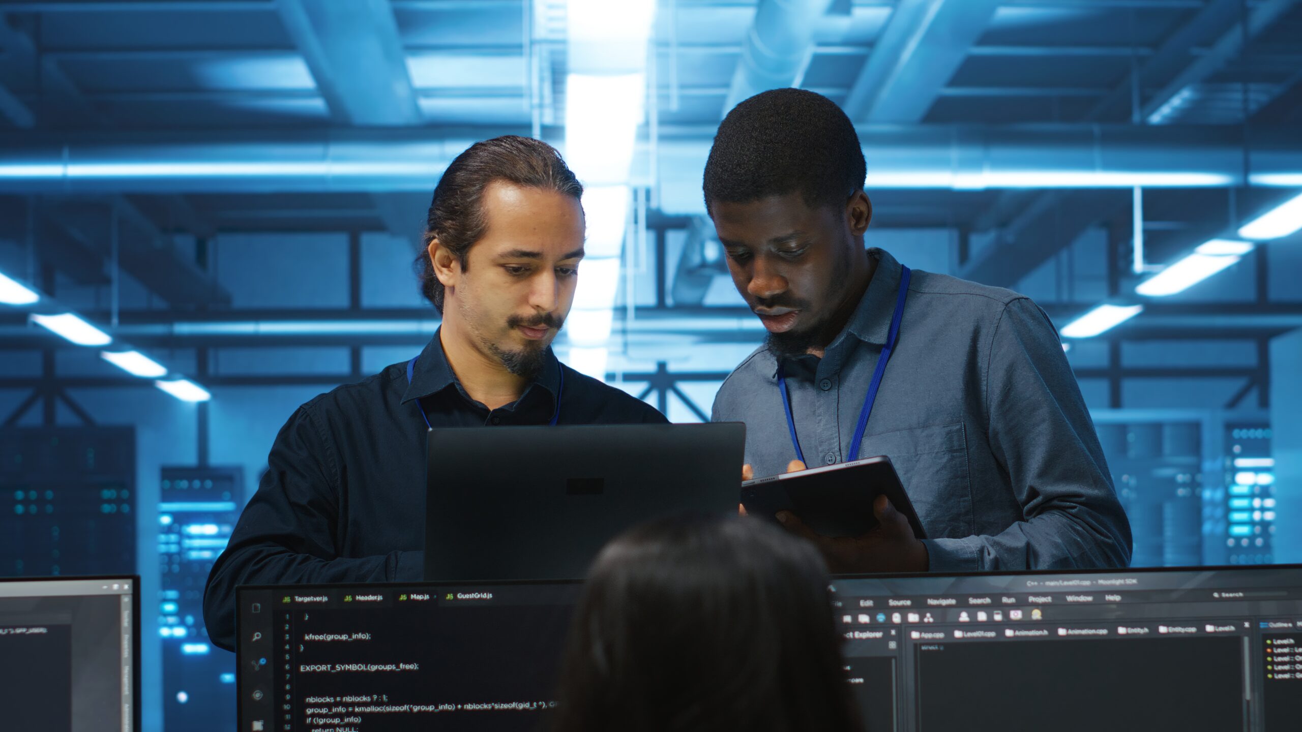 Multiethnic coworkers in server room collaborating to fix servers providing computing resources for workloads. Diverse team of admins supervising data center supercomputers